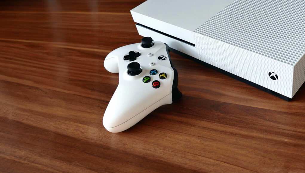 Valkoinen Xbox-konsoli puupöydällä.