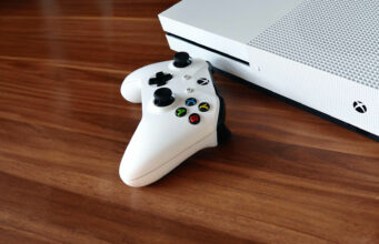 Microsoft yksinkertaistaa peliliiketoimintaansa Valkoinen Xbox-konsoli puupöydällä.