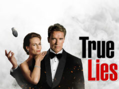 True Lies -arvostelu (4K UHD Blu-ray) – Terminatorin tekijöiden helmi Jamie Lee Curtis ja Arnold Schwarzenegger poseeraavat yhdessä. Arska heittää käsikranaatin ilmaan. Taustalla on savua.