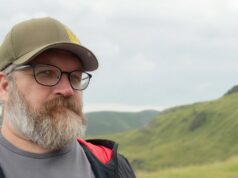 RedLynx-veteraani Antti Ilvessuo jätti Ubisoftin – näin uusi studio potkii pelialaa terveempään suuntaan Lähikuva miehestä, jolla on harmaantunut parta, mustat silmälasit ja oliivinvihreä lippalakki, jossa on keltainen symboli. Hän katsoo suoraan kameraan rauhallinen ilme kasvoillaan. Taustalla näkyy sumuisia, vihreitä kukkuloita pilvisen taivaan alla.