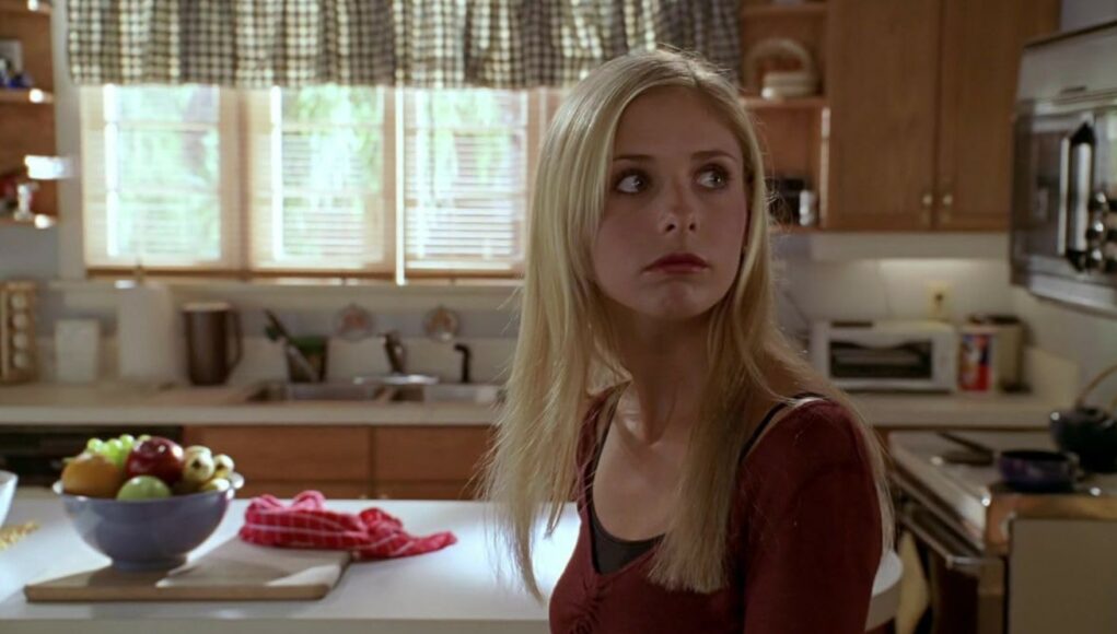 Buffy Summers (Sarah Michelle Gellar) katsoo huolestuneena olkansa yli keittiössä televisiosarjassa Buffy, vampyyrintappaja.