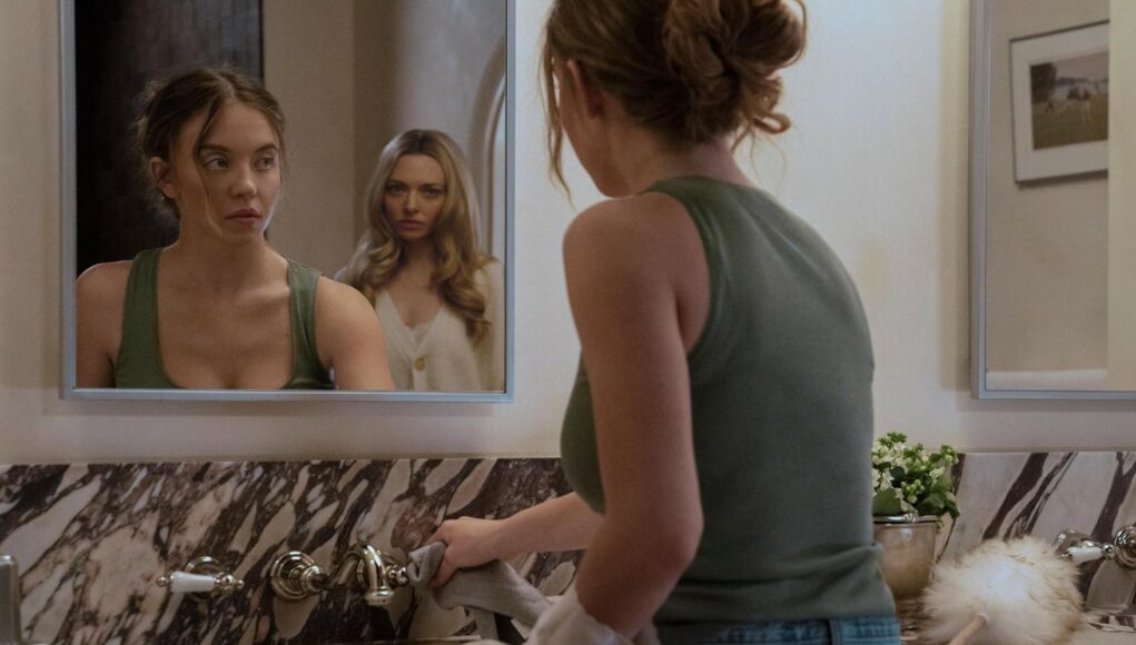 Kohtaus elokuvasta, jossa vihreään toppiin pukeutunut nainen pyyhkii kylpyhuoneen marmoritasoa. Hän katsoo peiliin, jonka heijastuksessa näkyy hänen takanaan seisova toinen, vaaleatukkainen nainen, jolla on yllään valkoinen neuletakki. Tunnelma on jännittynyt ja molempien ilmeet ovat vakavat.