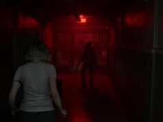 Resident Evil Requiem sai valokuvatilan ja muita päivityksiä Pelinäkymä hämärästä ja pelottavasta sairaalan tai vankilan käytävästä, jota valaisee vain punainen hätävalo ja EXIT-kyltti. Etualalla on vaaleatukkainen nainen selin, ja käytävän päässä häämöttää kaksi tummaa, uhkaavaa hahmoa kaltereiden takana.