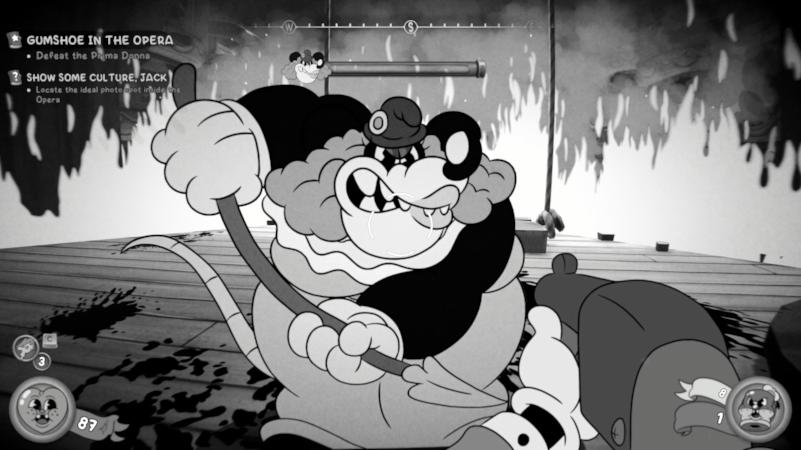 Mustavalkoinen ja rakeinen kuvakaappaus retrohenkisestä videopelistä, jossa on käytetty vanhaa filmimateriaalia jäljittelelevää suttuisuutta. Ensimmäisen persoonan näkymässä pelaaja tähtää aseella kookasta, ilkeästi virnistävää hiirihahmoa, jolla on yllään oopperatyylinen asu ja peruukki. Taustalla näkyy liekkejä tai savua, ja ruudun vasemmassa yläkulmassa on tehtäväteksti ”GUMSHOE IN THE OPERA – Defeat the Prima Donna”. Lattialla on tummia roiskeita, ja kuvan reunoilla näkyy pelin käyttöliittymäsymboleita.