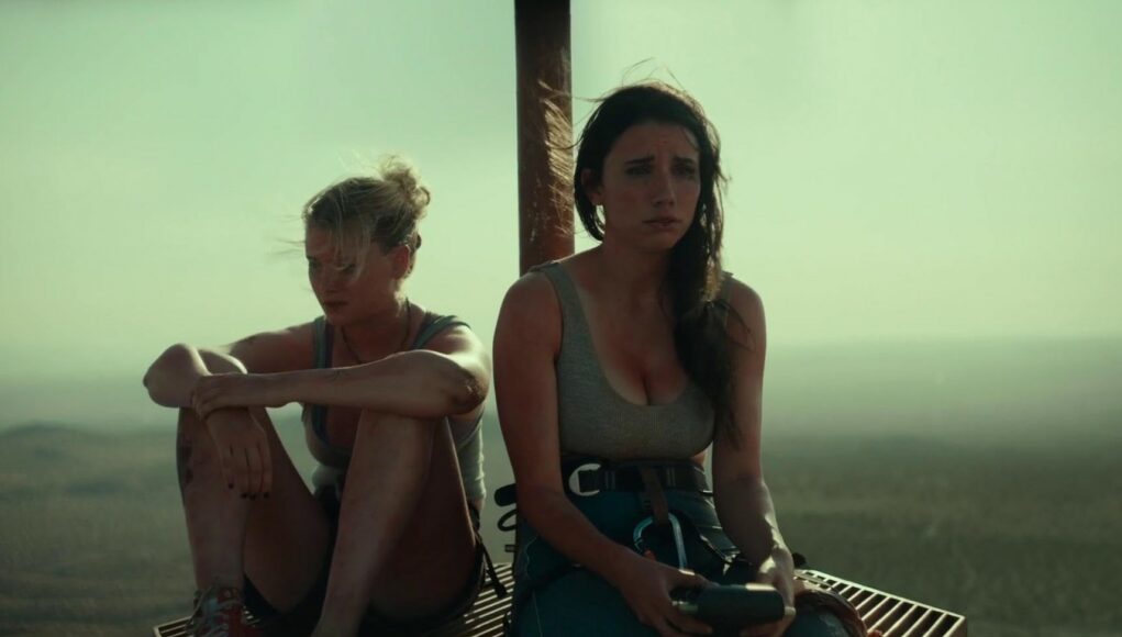 Kaksi naista istuu uupuneen ja järkyttyneen oloisena korkealla sijaitsevalla metallisella ritilätasolla. Taustalla näkyy sumuinen ja laaja autiomaamaisema. Molemmilla on yllään kiipeilyvarusteita, ja heidän kasvonsa ovat likaiset.