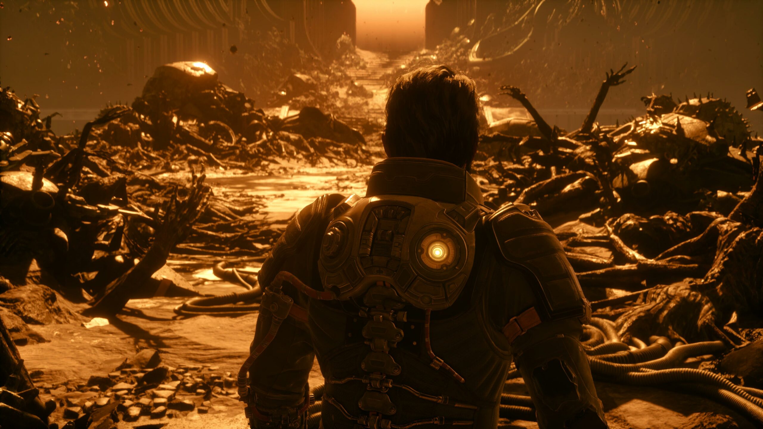 Takaapäin kuvattu otos haarniskaan pukeutuneesta hahmosta, joka katsoo yli oranssina hehkuvan, apokalyptisen maiseman. Maa on täynnä metalliromua, putkia ja epämääräisiä mekaanisia jäänteitä, jotka kylpevät paksussa, pölyisessä valossa. Haarniskan selkäosassa palaa pieni keltainen merkkivalo, ja kaukaisuudessa häämöttää valtava portti tai aukko, josta siivilöityy kirkasta valoa.