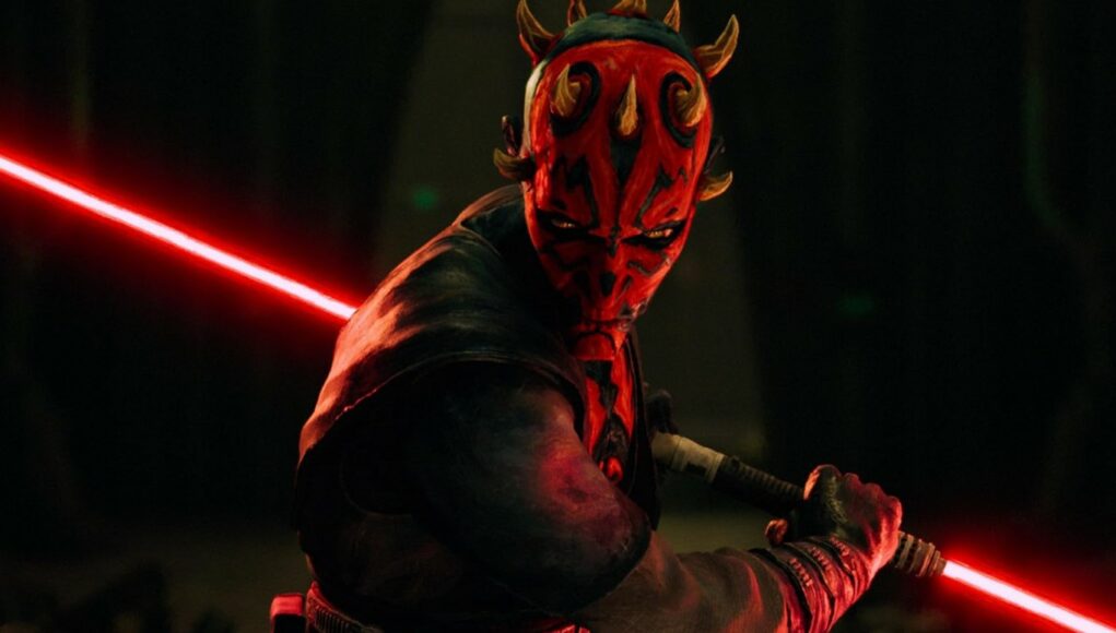 Lähikuva Darth Maulista, jolla on punamusta kasvomaski ja sarvet päässään. Hän pitelee kaksiteräistä punaista valomiekkaa ja katsoo uhkaavasti kohti kameraa hämärässä ympäristössä. Valomiekan punainen hehku valaisee osan hänen kasvoistaan ja vartalostaan.