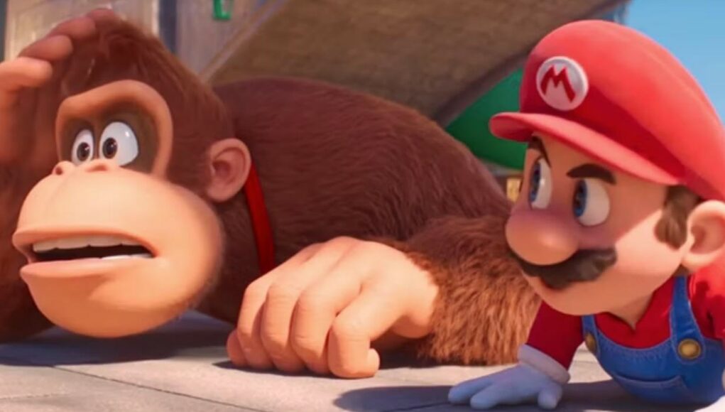 Lähikuva animaatioelokuvasta The Super Mario Bros. Movie. Kuvassa Donkey Kong ja Mario makaavat maassa vierekkäin katsoen hämmentyneinä tai huolestuneina sivulle. Donkey Kong on suuri ruskea gorilla, joka raapii päätään, ja Mariolla on yllään tunnusomainen punainen lippalakki, punainen paita ja siniset farkkuhaalarit. Tausta on kirkas ja aurinkoinen.