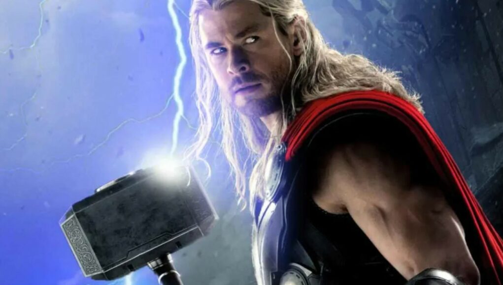 Sankarillinen lähikuva Thorista (Chris Hemsworth), jolla on pitkät vaaleat hiukset ja yllään punainen viitta sekä metallinen haarniska. Hän pitelee kädessään Mjölnir-vasaraa, johon iskee kirkas salama pimeää ja myrskyistä taivasta vasten. Thorin ilme on päättäväinen ja hänen silmänsä hohtavat heikosti salaman voimasta.