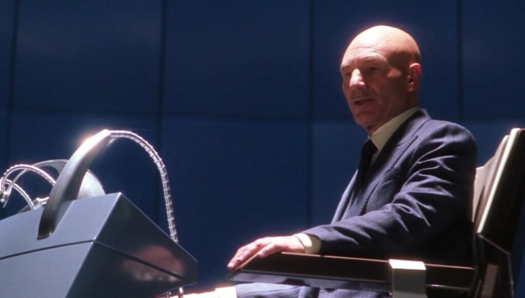 x-men-patrick-stewart Sivukuva Patrick Stewartista professori Charles Xavierin roolissa elokuvasta X-Men. Kalju mies istuu futuristisessa pyörätuolissa sinistä seinää vasten. Hänen kätensä lepää tuolin käsinojalla, ja hänen edessään näkyy osa Cerebro-laitteiston metallista rakennetta. Xavierilla on yllään tummansininen puku, vaalea kauluspaita ja tumma solmio.