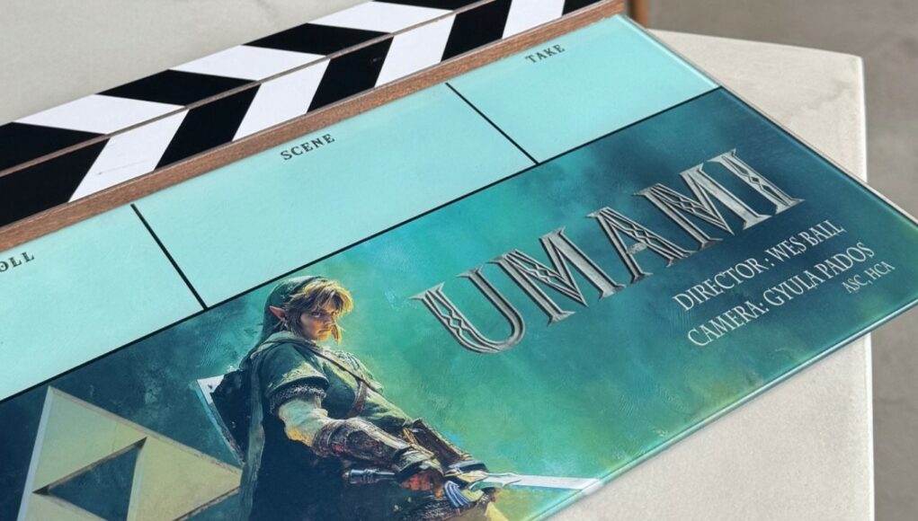 Lähikuva elokuvatuotannossa käytettävästä klaffista, joka on kallellaan vaalealla alustalla. Klaffin alaosaan on painettu näyttävä kuva Link-hahmosta vihreässä asussaan pitelemässä miekkaa. Kuvan vieressä on teksti ”UMAMI” suurilla kirjaimilla sekä tiedot ohjaajasta (Wes Ball) ja kuvaajasta (Gyula Pados). Vasemmassa alakulmassa näkyy Triforce-symboli. Klaffin yläosassa on perinteinen mustavalkoinen raitakuvio ja paikat kohtauksen ja oton numeroille.