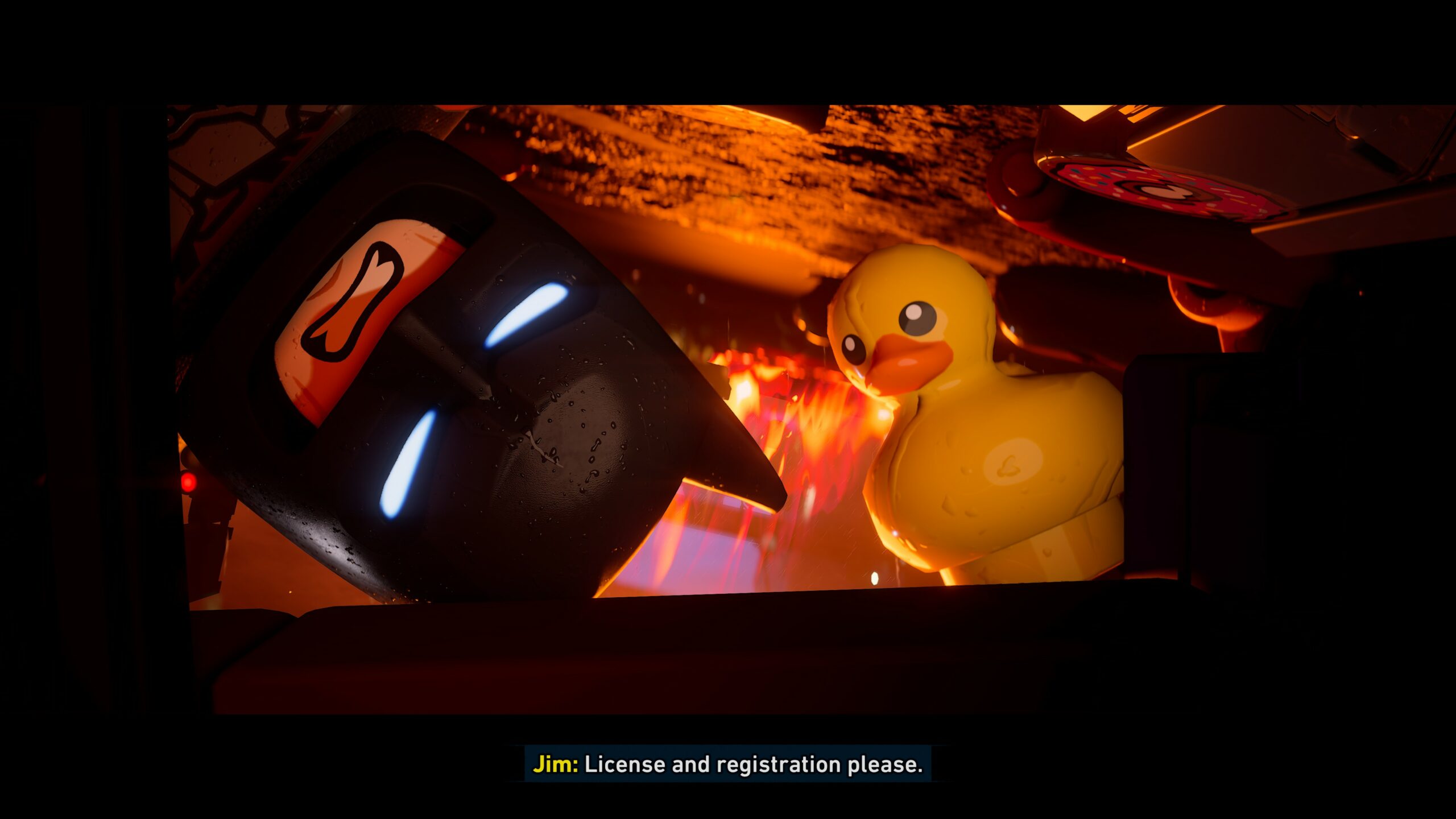 Lähikuva videopelin välikohtauksesta, jossa Lego Batman -hahmo katsoo vinosti ja hämmentyneenä auton tai kulkuvälineen ikkunasta sisään. Hänen vieressään taustalla näkyy suuri, keltainen kumiankka lämpimässä, oranssissa valaistuksessa. Kuvan alalaidassa on tekstitys: ”Jim: License and registration please.”