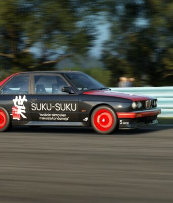 Tältä näyttää Assetto Corsa EVO -peliin tuleva modien content manager ja vanhojen karttojen muunnin Musta ja punainen kilpa-auto, jonka kyljessä on teksti "SUKU-SUKU" sekä maininta "Isoäidin sämpylien makuisia kondomeja", ajaa radalla sivuttaisliikkeessä sumennetun taustan edessä.