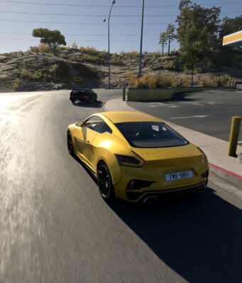 BeamNG.drive sai suurimman päivityksensä tähän mennessä – grafiikat ja äänet täysin uusiksi Keltainen urheiluauto ajaa aurinkoisella tiellä huoltoaseman ja kukkulan läheisyydessä.