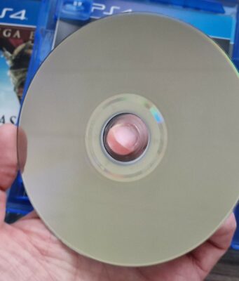 EU ei voi vaikuttaa siihen, että Sony luopuu fyysisistä pelilevyistä tulevaisuudessa Käsi pitelee PlayStation 4 -pelin levyä, jonka taustalla näkyy pelikotelo.