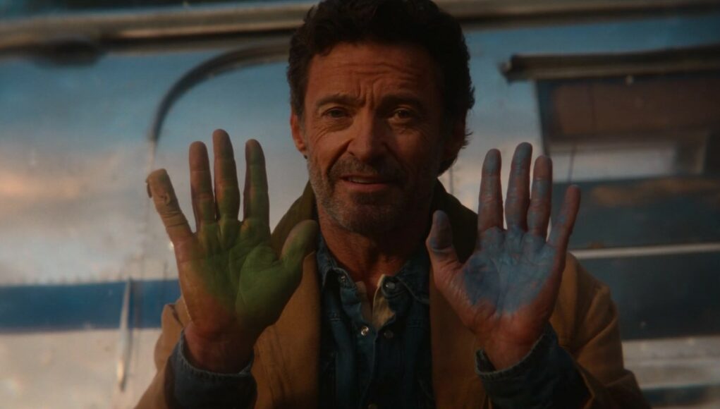 hugh-jackman-lammasetsivat Mies näyttää kämmeniään, jotka on värjätty toisesta kädestä vihreiksi ja toisesta sinisiksi.