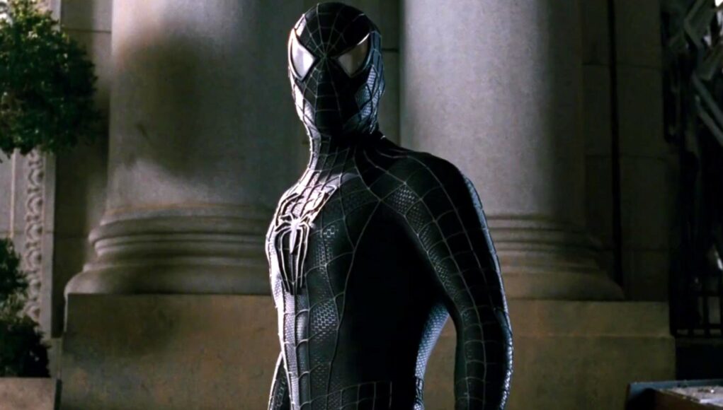 spider-man-symbiottipuku Hämähäkkimies mustassa puvussaan seisoo vakavana pylväiden edessä.
