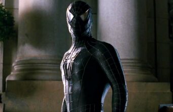Tom Holland vihjasi Hämähäkkimiehen tulevaisuudesta – fanit innostuivat oitis! Hämähäkkimies mustassa puvussaan seisoo vakavana pylväiden edessä.