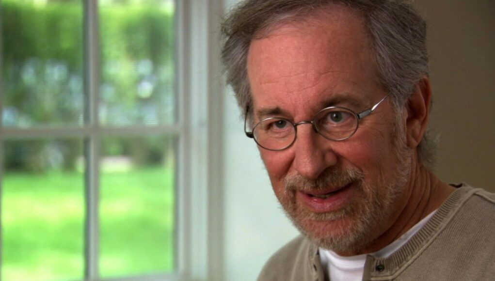 steven-spielberg Lähikuva Steven Spielbergistä, jolla on yllään vaalea pusero ja silmälasit, ikkunan edessä.