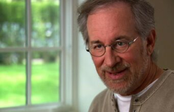 Steven Spielberg tekee pelottavasta Youtube-sarjasta kauhuelokuvan Lähikuva Steven Spielbergistä, jolla on yllään vaalea pusero ja silmälasit, ikkunan edessä.