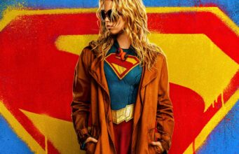Supergirl-elokuva jäämässä flopiksi – lipputulot laskivat 74 % avausviikonlopusta Aurinkolaseihin pukeutunut nainen, jolla on yllään supersankariasu ja ruskea takki, seisoo suuren graffitimaisen S-logon edessä.