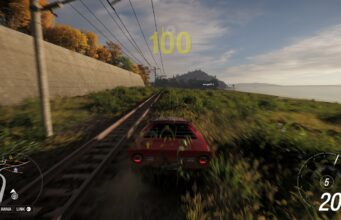 PS5-pelaajat joutuvat vielä odottamaan Forza Horizon 6:ta Pelinäkymä ajopelistä, jossa punainen urheiluauto ajaa vauhdilla rautatiekiskojen vieressä pitkin ruohoista penkereitä rannan ja betoniseinän välissä; näytöllä näkyvät nopeusmittari ja minimappi.