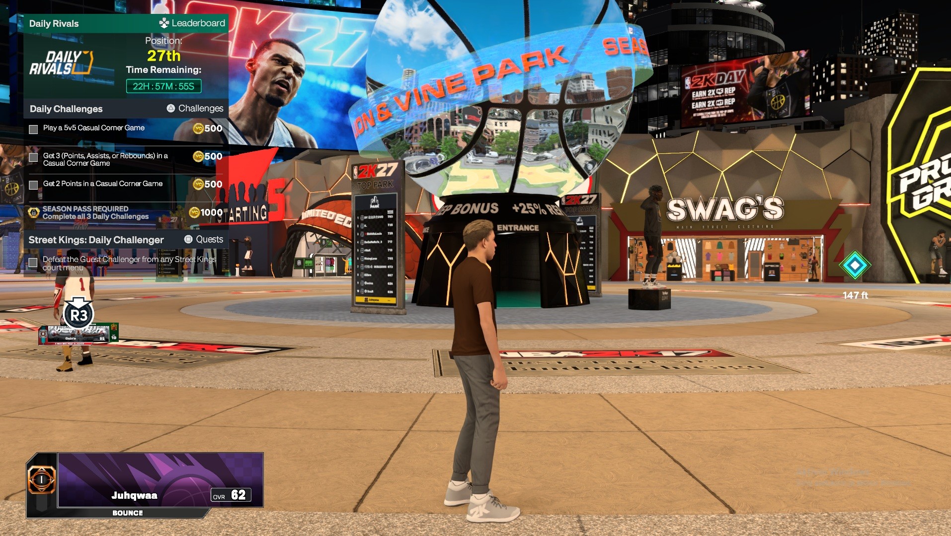 NBA 2K27 -pelin virtuaalinen ulkoilmaelämäalue (The City/Neighborhood), jossa pelaajahahmo seisoo torimaisella aukiolla suuren jalkapallon tai koripalloveistoksen edessä suurten mainostaulujen ympäröimänä.